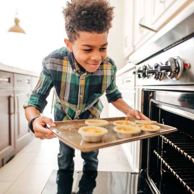 adolescent boy putting mini pies in the oven