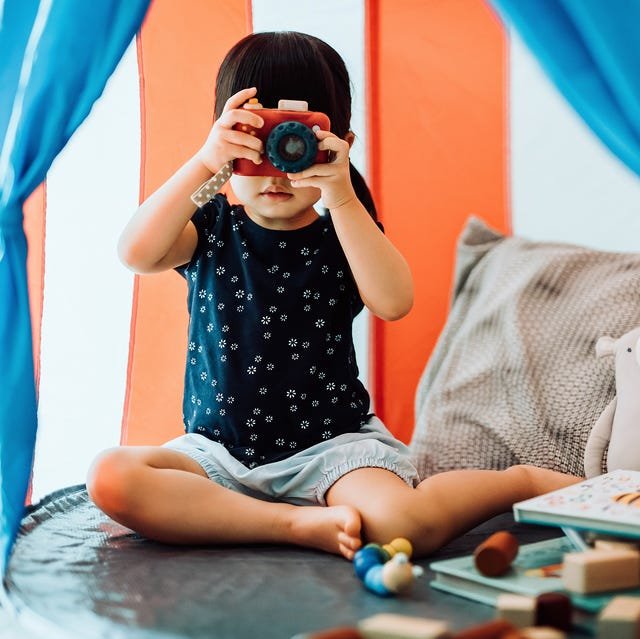 2 year old playing in play tent with camera blocks and books